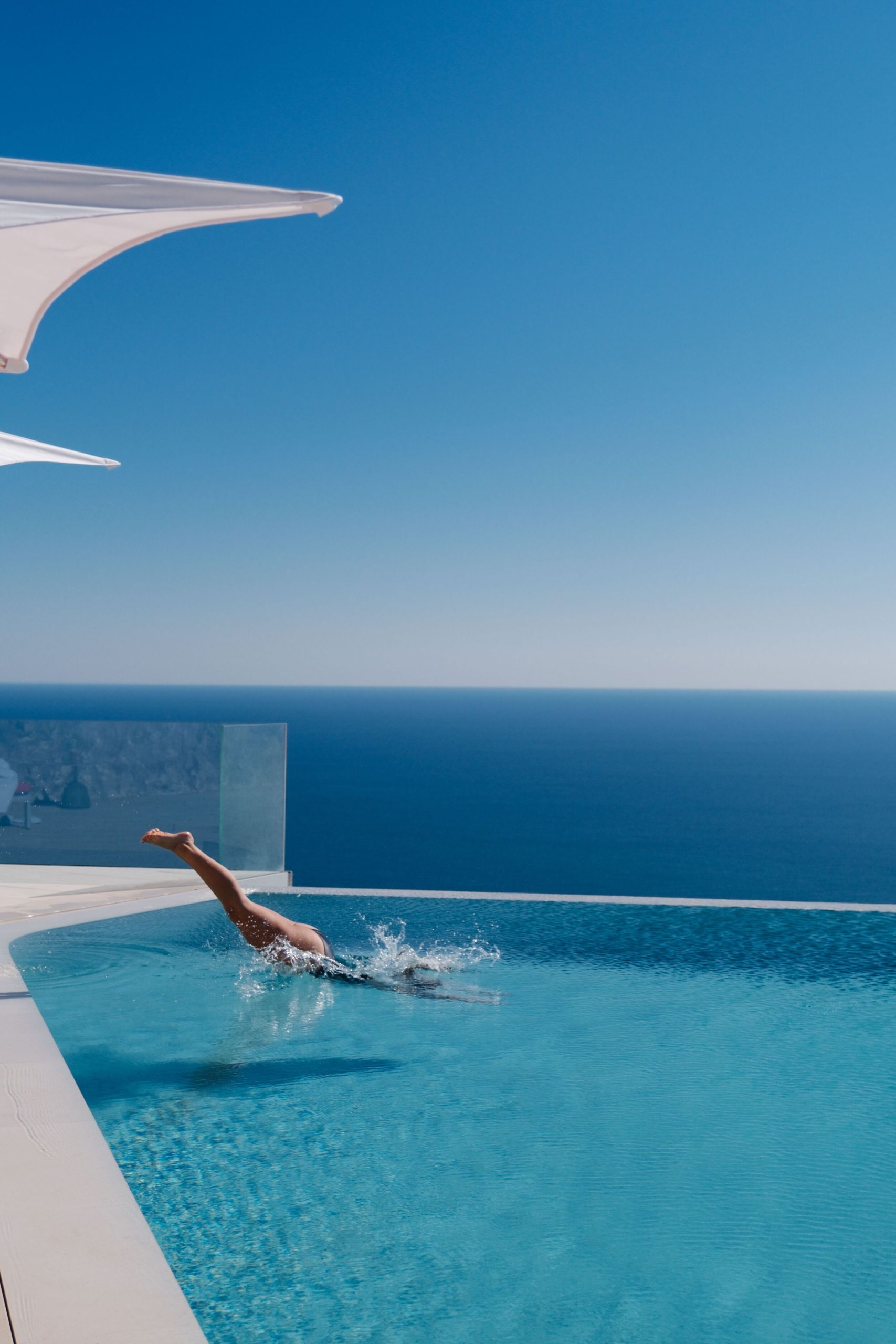 Infinity pool at Maybourne Riviera overlooking the Mediterranean, with orange sunbeds in the foreground