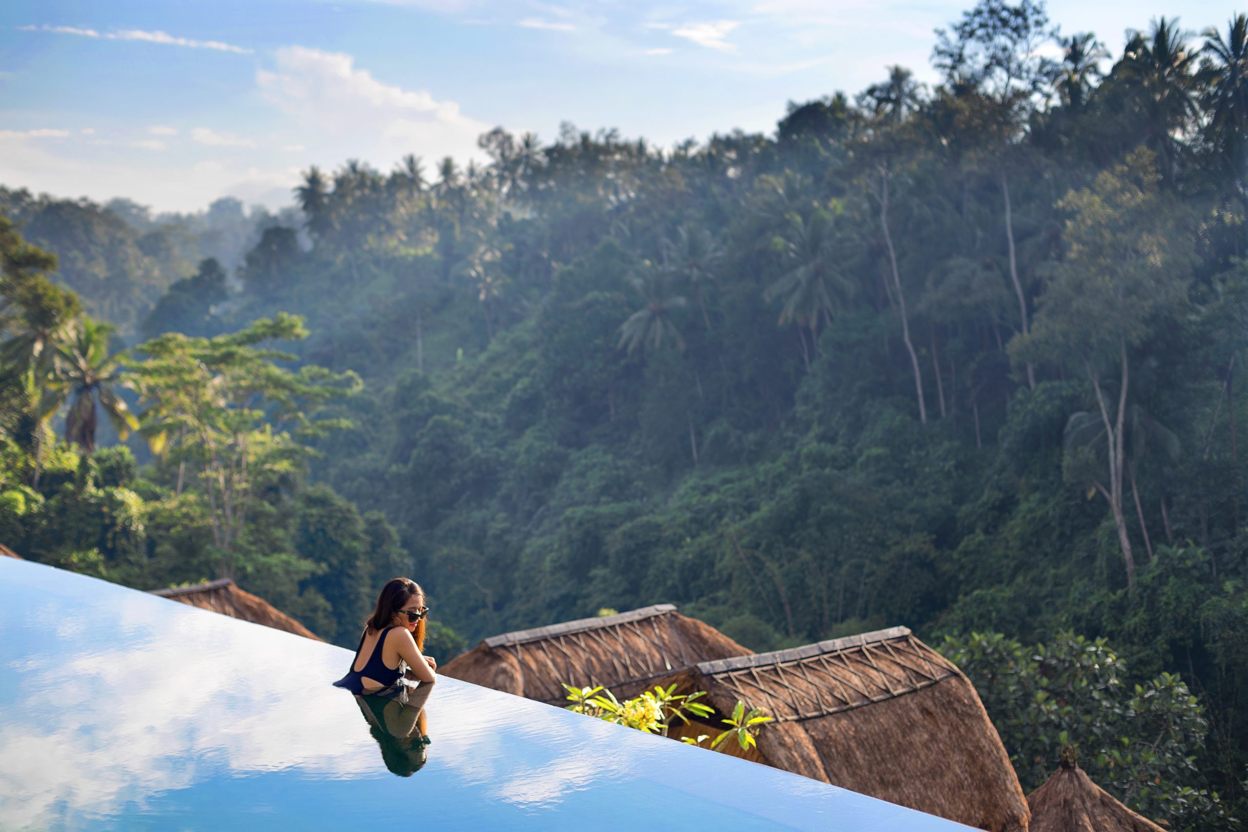 Infinity pool at Viceroy Bali overlooking a jungle ravine, framed by thatched-roof bales